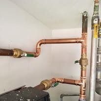 Technician installing or repairing a heating system in an indoor workshop setting.